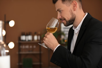 Young man with glass of wine indoors