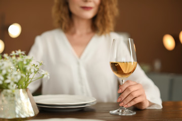Woman with glass of wine at table in restaurant