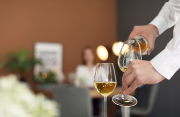 Man pouring wine into glass in restaurant