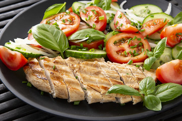 Vegetable salad and grilled chicken on a black background. Healthy food. Diet.