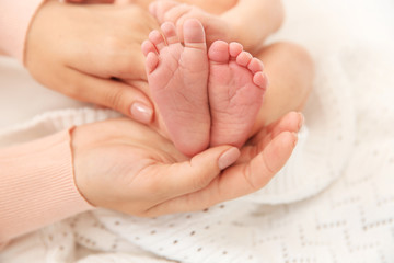 Obraz na płótnie Canvas Mother holding little baby feet in hands