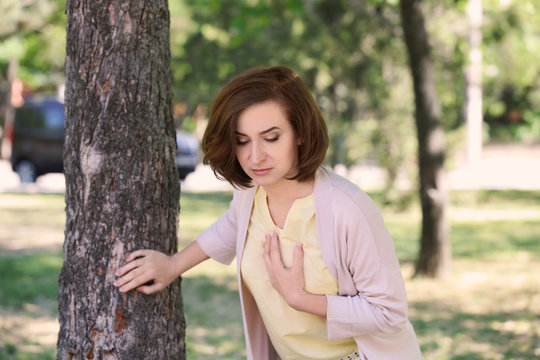 Mature woman having heart attack near tree in park