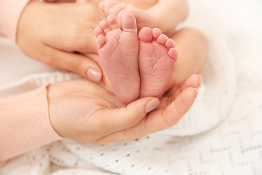 Mother holding little baby feet in hands