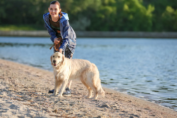 Young woman with her dog together on beach. Pet care