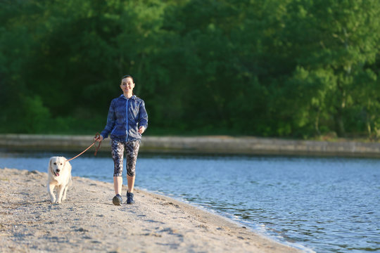 Young woman with her dog together on beach. Pet care