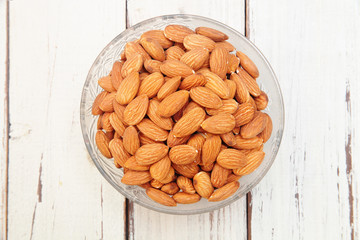 Almonds  in glass bowl on wooden table       