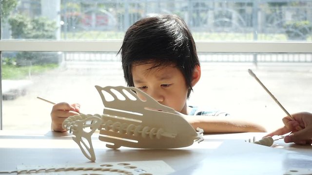 Cute Asian child  builds a toy of wood slow motion 