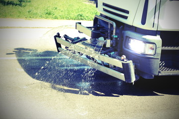 roadwashing truck while spraying water on the dirty asphalt