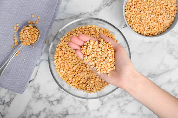Woman holding dried peas over table, top view