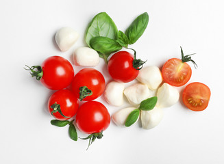 Ripe red tomatoes, mozzarella cheese balls and basil on white background, top view