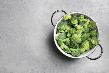 Colander with fresh green broccoli on grey background, top view