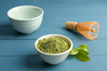 Bowl with matcha tea and green leaves on wooden table