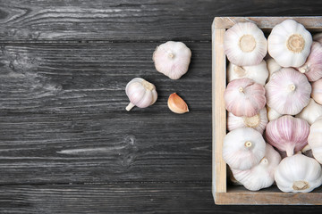 Fototapeta na wymiar Crate with fresh garlic bulbs on wooden background, top view