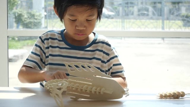 Cute Asian child  builds a toy of wood slow motion 