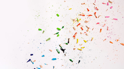 Flat lay of colorful wooden pencil shavings scattered around on a white paper.