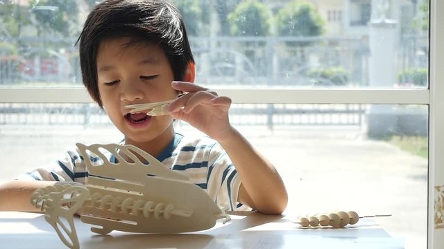 Cute Asian child  builds a toy of wood slow motion 