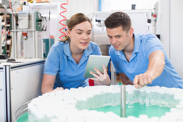 Engineer And Apprentice With Digital Tablet Working In Bottle Capping Factory