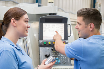 Fototapeta na wymiar Engineer Instructing Female Apprentice On Use Of CNC Machine