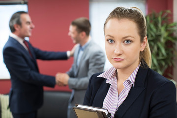 Portrait Of Unhappy Businesswoman With Male Colleague Being Congratulated