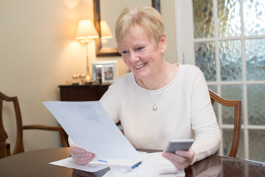 Happy Senior Woman Reviewing Domestic Finances At Home