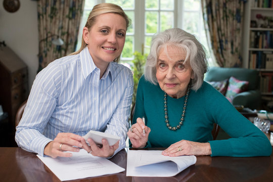 Portrait Of Woman Helping Senior Neighbor With Paperwork