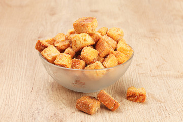 Delicious fried croutons in glass bowl on wooden table  