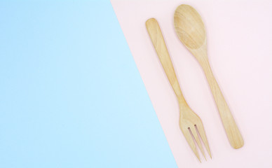 wooden spoon and fork on pink and blue background