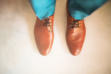 Man wearing shoes on gray background. Clothing concept, groom getting ready before ceremony. Body detail of businessman.