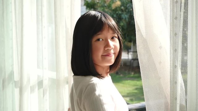 close up of happy Asian girl opening window curtains slow motion 