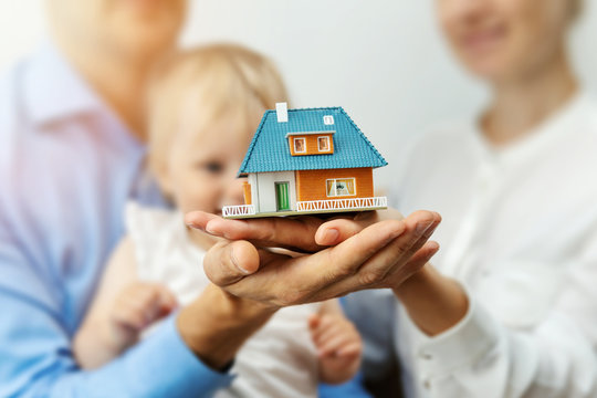 new home concept - young family with dream house scale model in hands