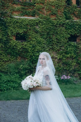 beautiful young bride in garden in front of ancient building covered with vine