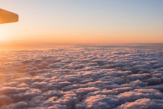 Evening sunset sky from the window of the airplane. View of the beautiful sky and clouds from the window of the airplane. Wing of an airplane against a beautiful sunset sky.
