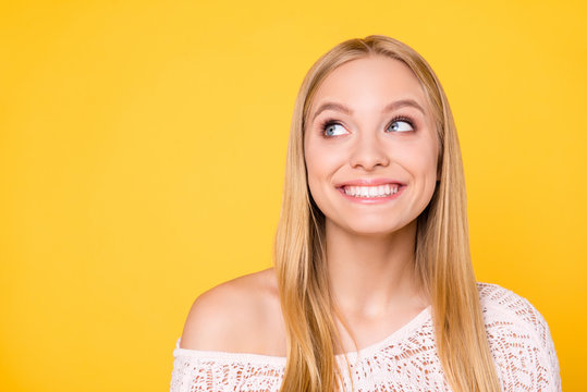 Portrait of cheerful toothy girl with naked shoulder looking with eyes at copyspace empty place having white straight healthy teeth isolated on yellow background
