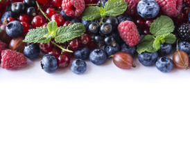 Ripe currants, raspberries, blueberries, gooseberrie, blackberries with a mint leaf. Sweet and juicy fruits with copy space for text. Background of mix fruits on a white background. Top view.