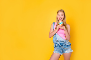 Portrait of tempting sexy girl licking her upper lip looking at vanilla caramel ice cream in waffle cone in hands isolated on yellow background, good summer vibes only concept