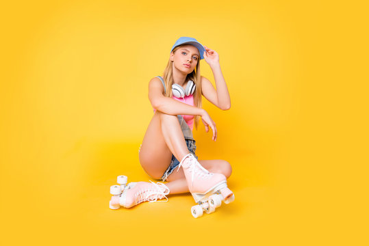 Portrait of pretty attractive girl wearing baseball cap roller skates with headset on neck looking at camera having confident sight isolated on yellow background, street urban outdoor style - Powered by Adobe