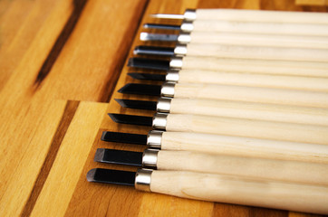 a set of different tools for cutting wood products, with a wooden handle on a wooden Board background