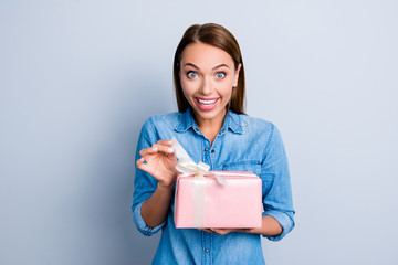 Fototapeta na wymiar Portrait of excited glad woman having present in hands wanted to open it looking at camera isolated on grey background