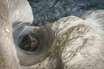View from above the hole, which was washed out by force of water within thousands of years. In the foreground you can see massive rocks, below you can see the river, whose work it was.