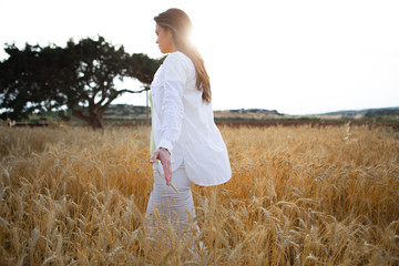 Peace and relaxation. Calm girl is walking on wheat field. Her eyes are closed with enjoyment