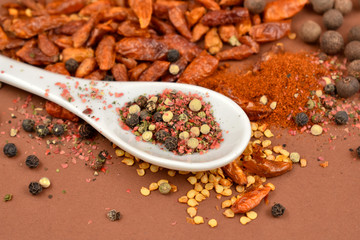 Spicy spice and spoon close-up stock photo images. Hot peppers and pepper images. Different types of spices images on a brown background. Aromatic spice collection. Spicy seasoning still life