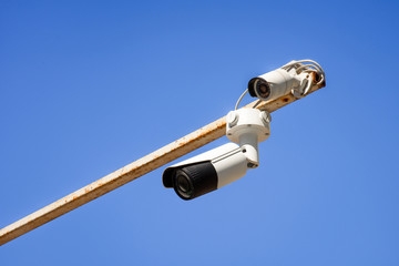 close up view of security cameras on pole against bright blue sky