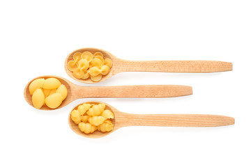 Wooden spoons with different types of pasta on white background