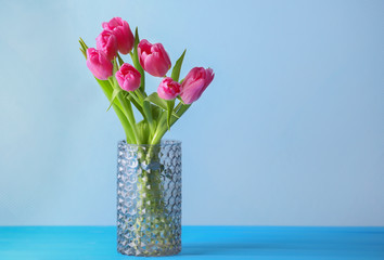 Vase with bouquet of beautiful tulips on color background