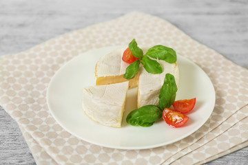 Delicious brie cheese with basil and cherry tomatoes on plate