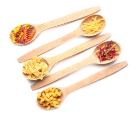 Wooden spoons with uncooked pasta on white background