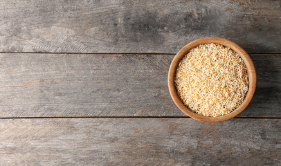 Bowl with uncooked pasta on wooden background