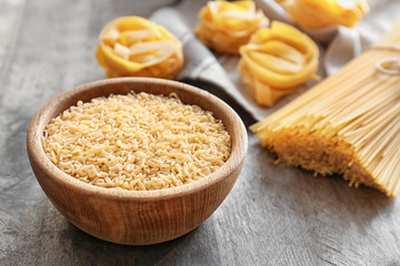 Bowl with uncooked pasta on table
