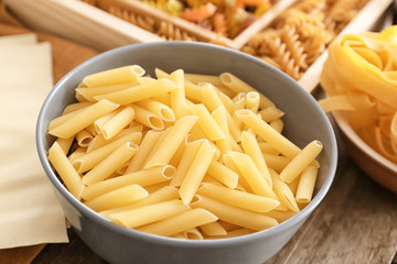 Bowl with uncooked pasta on table