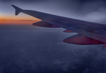 Fototapeta na wymiar Wing of a plane midair at sunset or sunrise